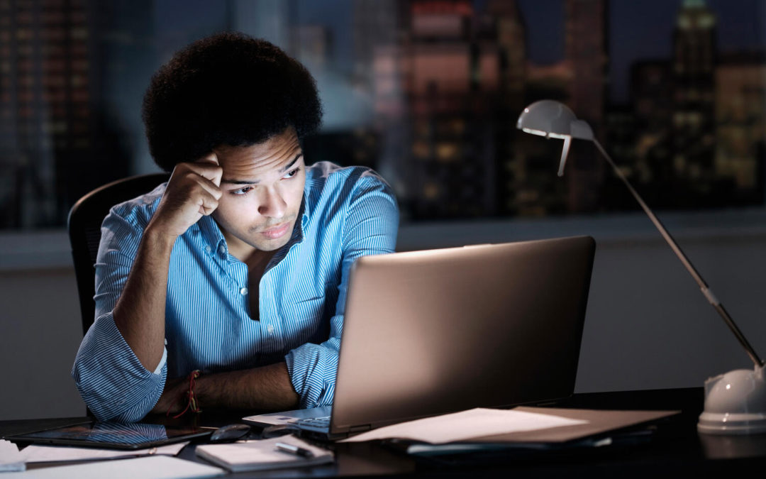 Mixed race businessman wearing blue shirt working late in dark office